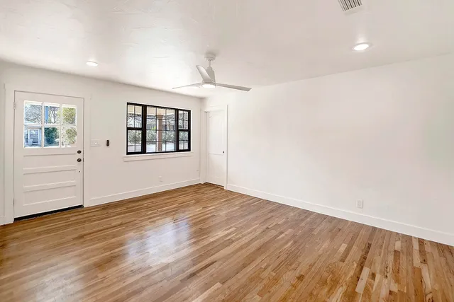 an empty room with wooden floor cabinet and windows