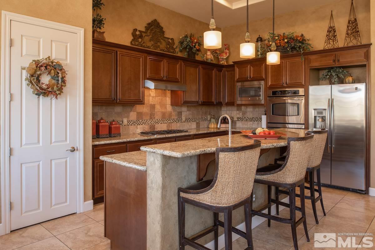 9895 Copenhagen Way Reno, NV 89521 - Photo 9 of 25 a kitchen with stainless steel appliances a dining table chairs and chandelier