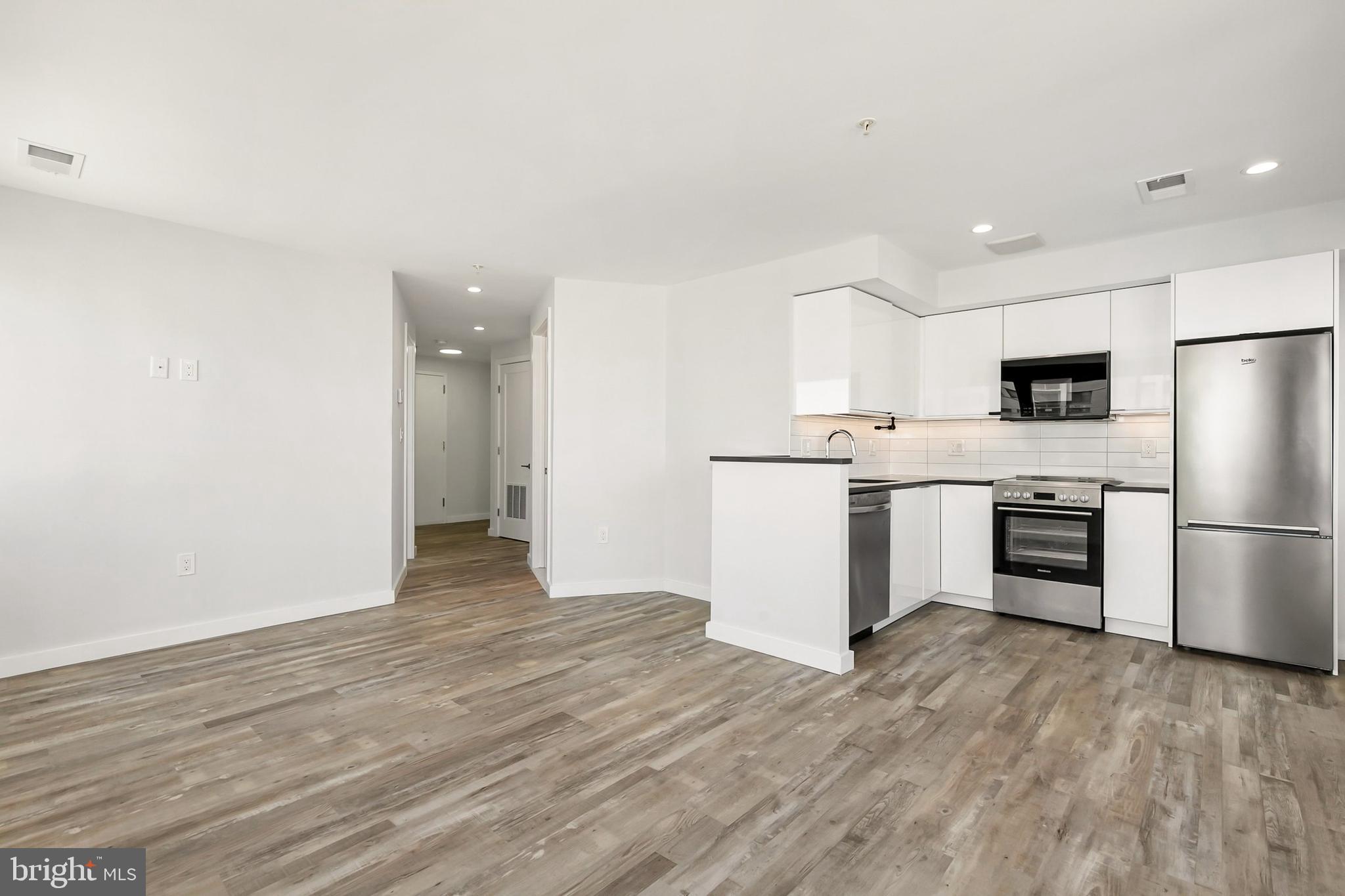 700 Roeder Road, Unit 603 Silver Spring, MD 20910 - Photo 4 of 21 a kitchen with a refrigerator a stove top oven and white cabinets