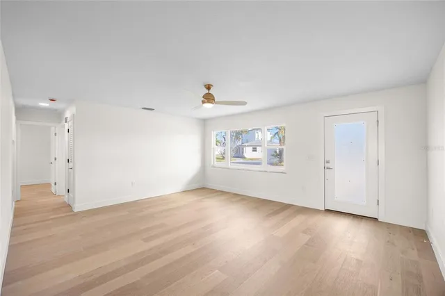 a view of an empty room with a window and wooden floor