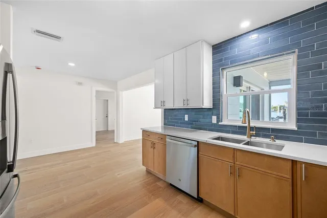 a kitchen with stainless steel appliances granite countertop a sink and cabinets with wooden floor