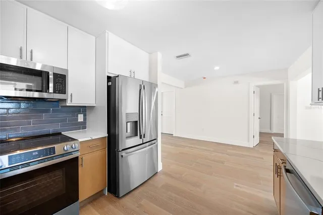 a kitchen with granite countertop a refrigerator and a stove top oven