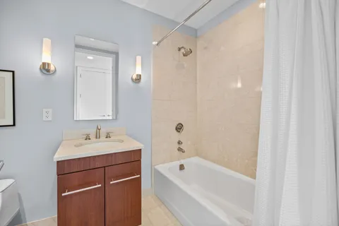 a bathroom with a tub sink vanity and mirror