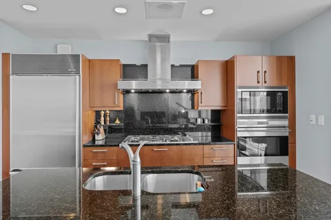 a kitchen with stainless steel appliances granite countertop a refrigerator and a stove