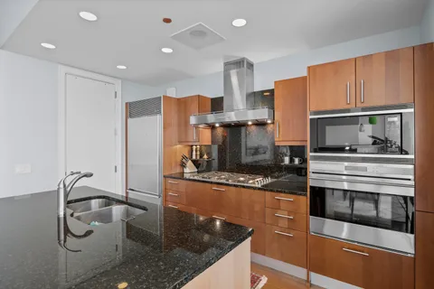 a kitchen with stainless steel appliances granite countertop a sink a stove and a refrigerator