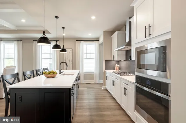 a large kitchen with kitchen island a stove a sink a center island and windows