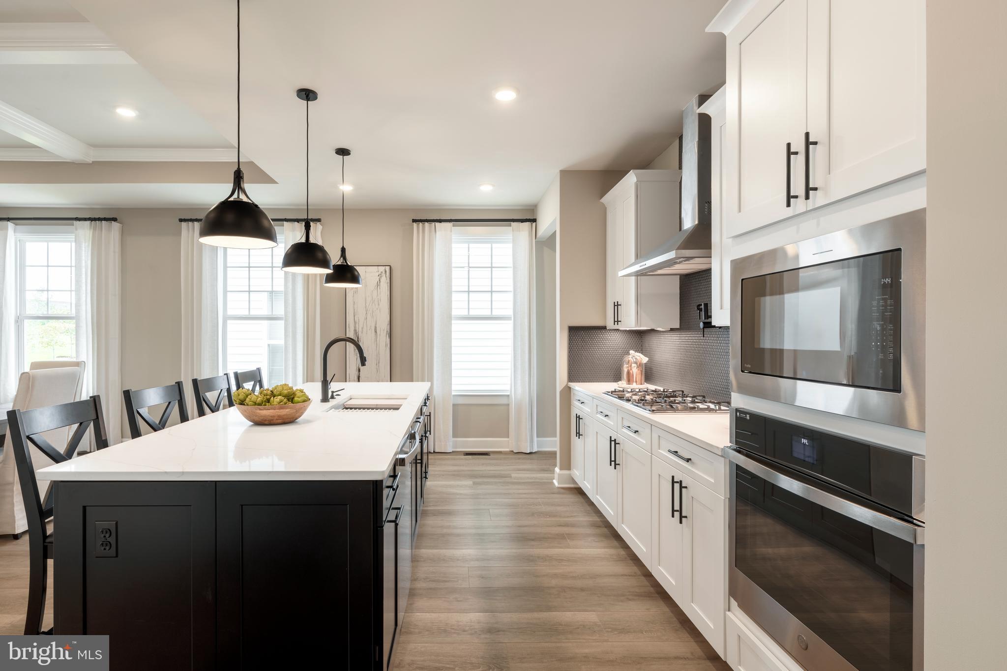 6497 Swimmer Row Way Columbia, MD 21044 - Photo 11 of 41 a large kitchen with kitchen island a stove a sink a center island and windows