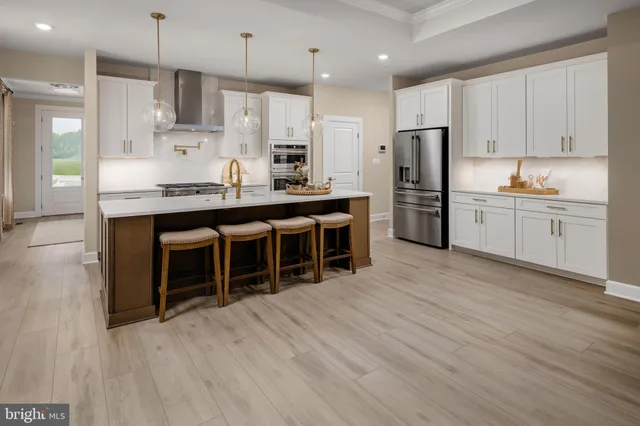 a large kitchen with stainless steel appliances granite countertop a stove a sink dishwasher and a refrigerator with wooden floor