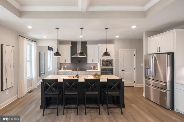 a kitchen with stainless steel appliances a dining table chairs refrigerator and cabinets