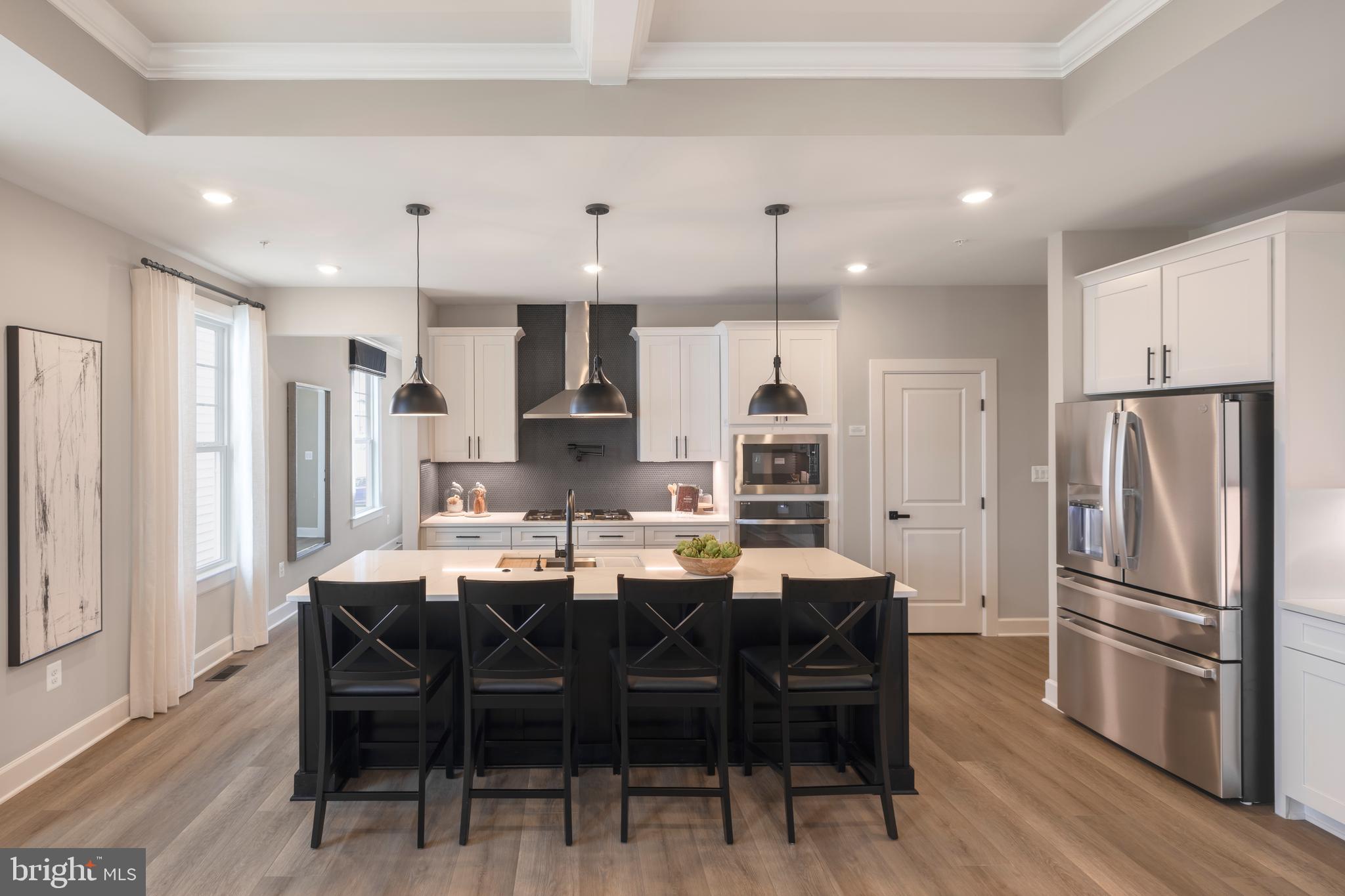 6497 Swimmer Row Way Columbia, MD 21044 - Photo 10 of 41 a kitchen with stainless steel appliances a dining table chairs refrigerator and cabinets
