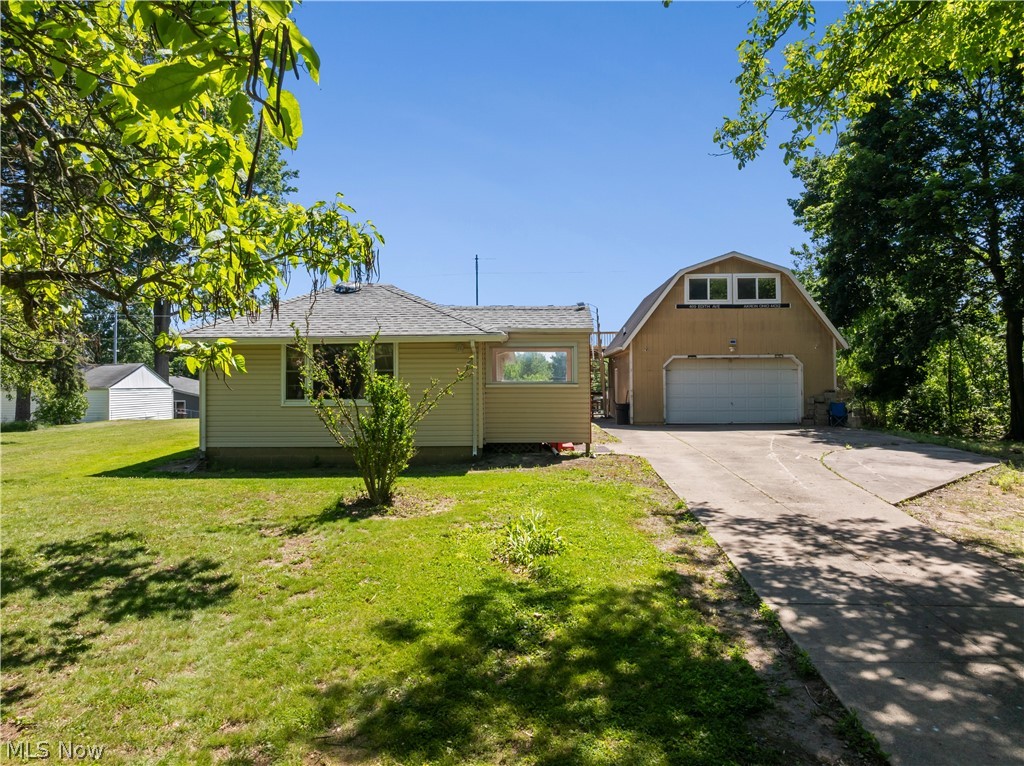 409 Edith Avenue Akron, OH 44312 - Photo 2 of 45 Gable roof home with light-toned siding, featuring a two-car garage with an overhead door, an additional upper-level window bank, and a concrete driveway