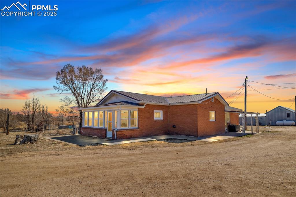 Back of property featuring brick siding, a metal roof, and a patio