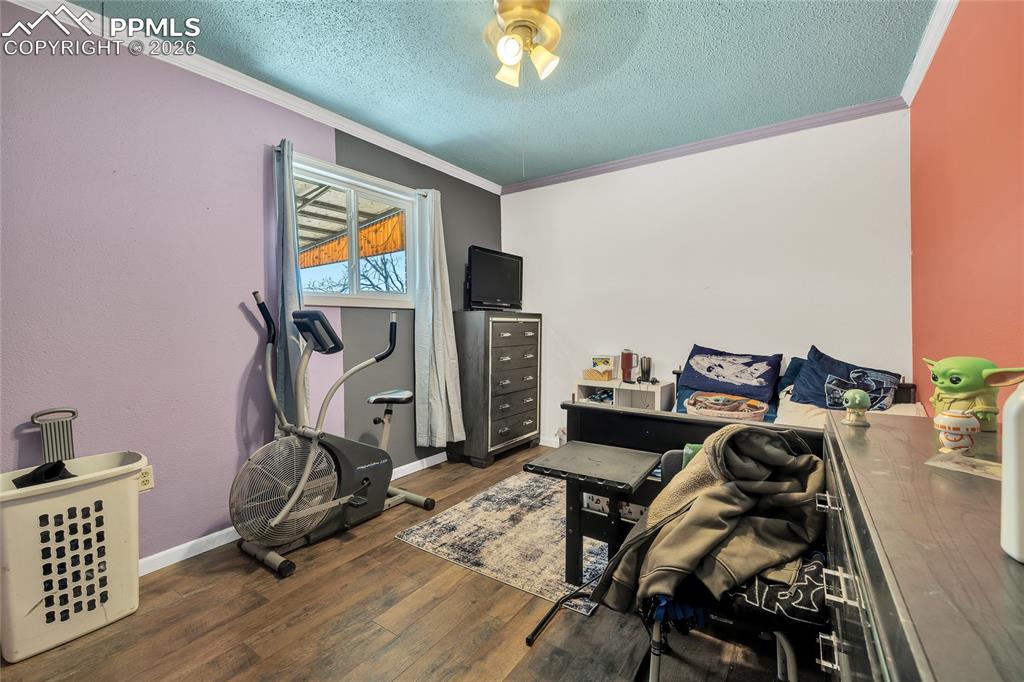 68300 Highway 50 Fowler, CO 81039 - Photo 15 of 49 Exercise area with dark wood-style flooring, a textured ceiling, ornamental molding, and ceiling fan