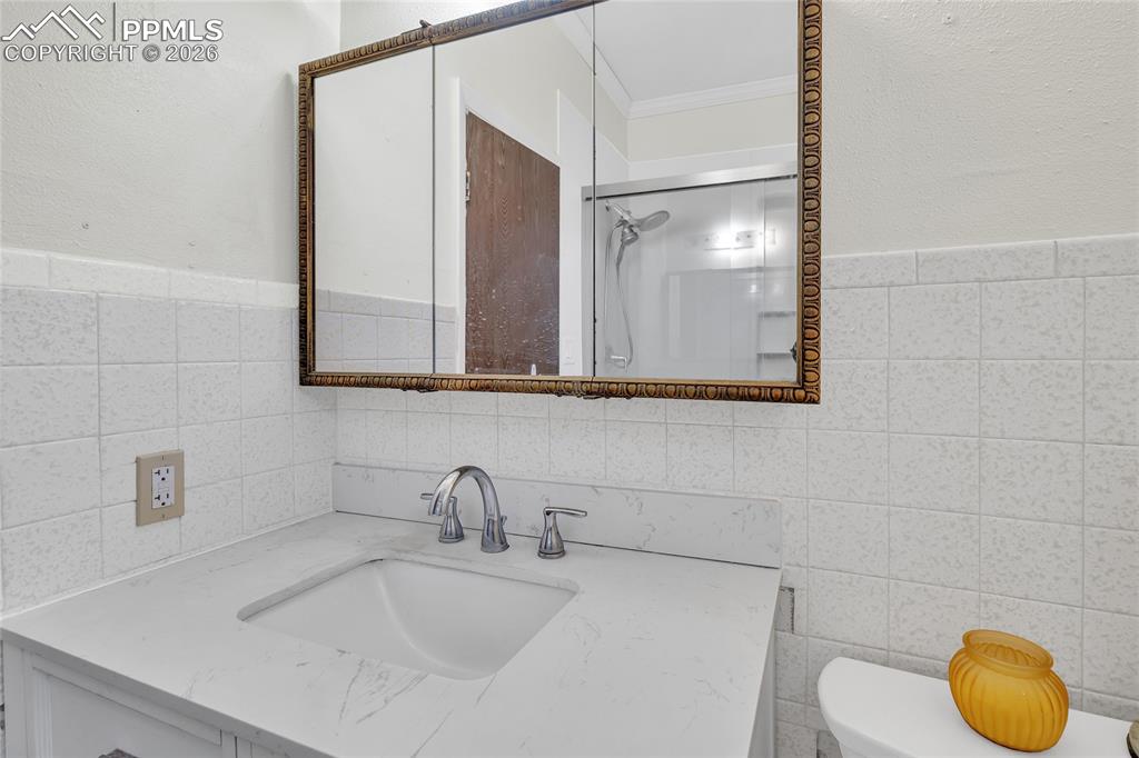 68300 Highway 50 Fowler, CO 81039 - Photo 16 of 49 Bathroom featuring vanity, a shower, crown molding, and tile walls