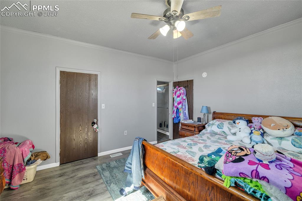 68300 Highway 50 Fowler, CO 81039 - Photo 17 of 47 Bedroom featuring wood finished floors, a ceiling fan, crown molding, and a textured ceiling