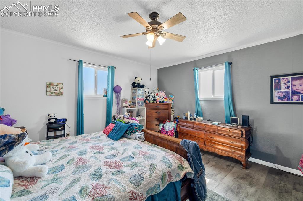 68300 Highway 50 Fowler, CO 81039 - Photo 19 of 47 Bedroom featuring dark wood-style floors, ceiling fan, a textured ceiling, and ornamental molding