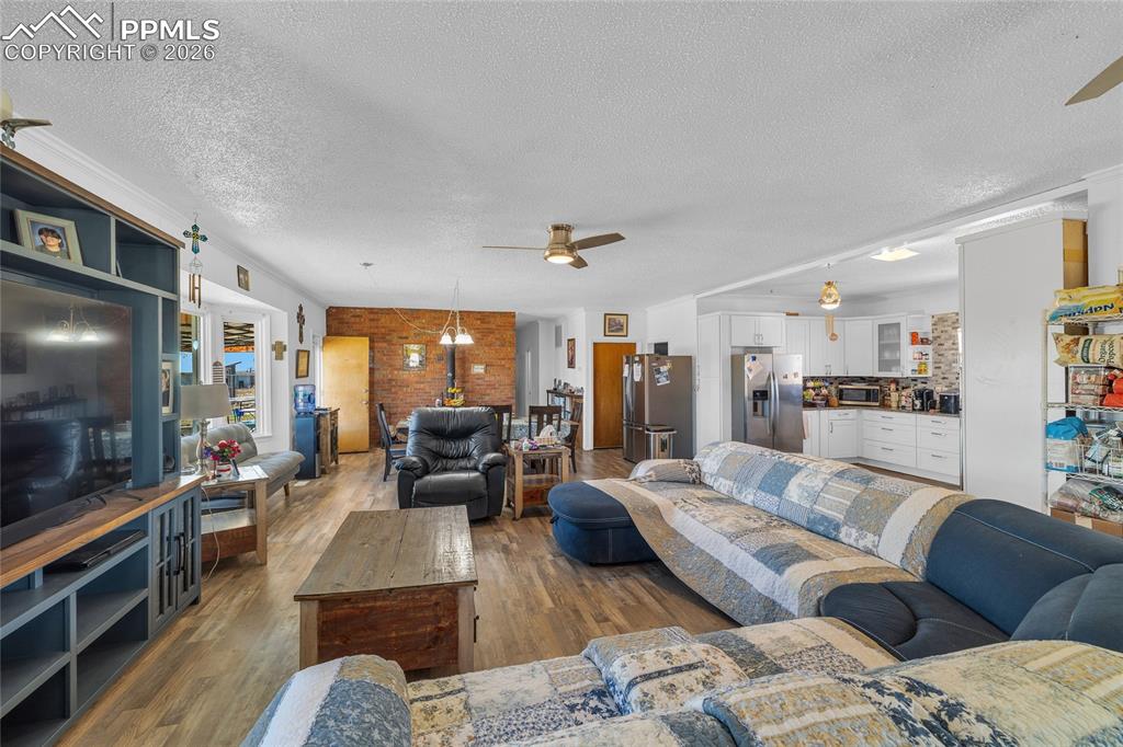 68300 Highway 50 Fowler, CO 81039 - Photo 22 of 47 Living room with ceiling fan, dark wood-style flooring, a textured ceiling, and brick wall