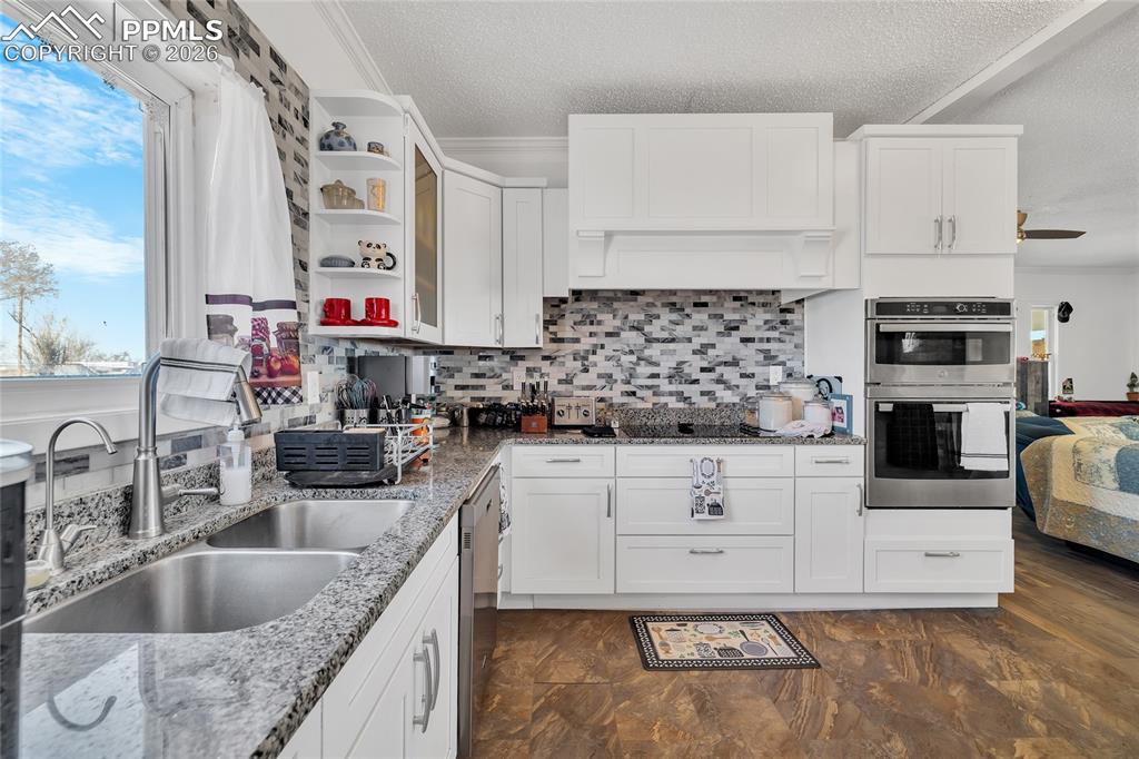 68300 Highway 50 Fowler, CO 81039 - Photo 28 of 49 Kitchen with white cabinets, open shelves, stainless steel appliances, light stone countertops, and a textured ceiling