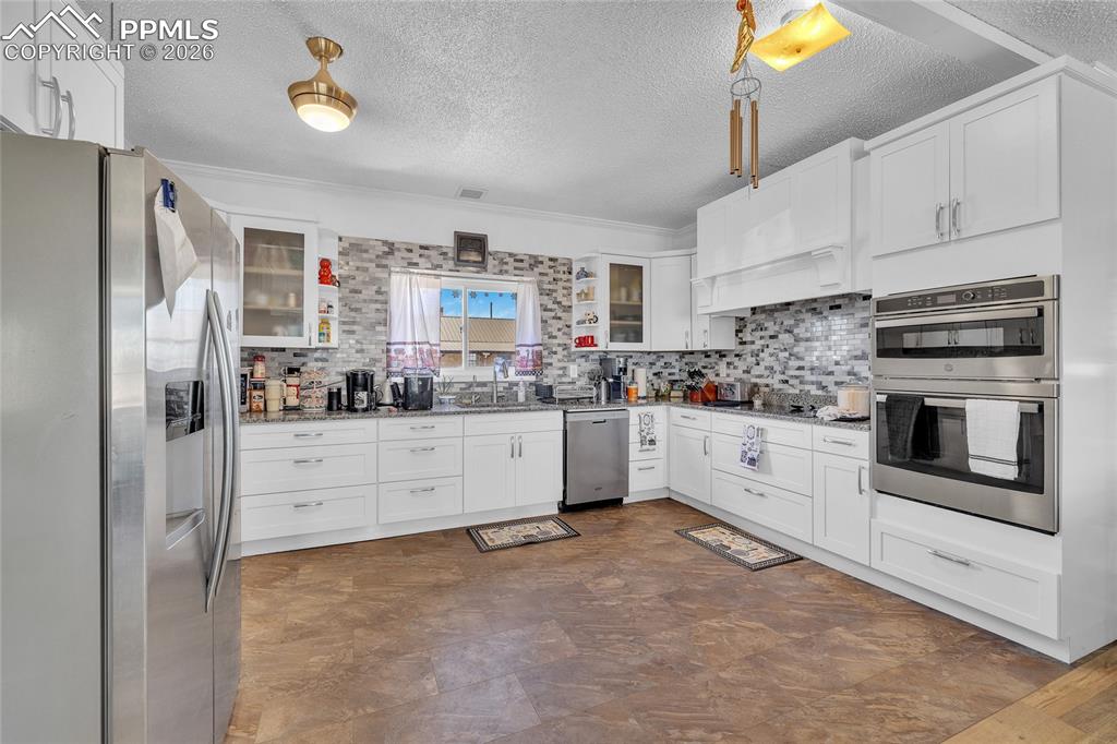 68300 Highway 50 Fowler, CO 81039 - Photo 29 of 47 Kitchen with stainless steel appliances, glass insert cabinets, white cabinets, crown molding, and a textured ceiling