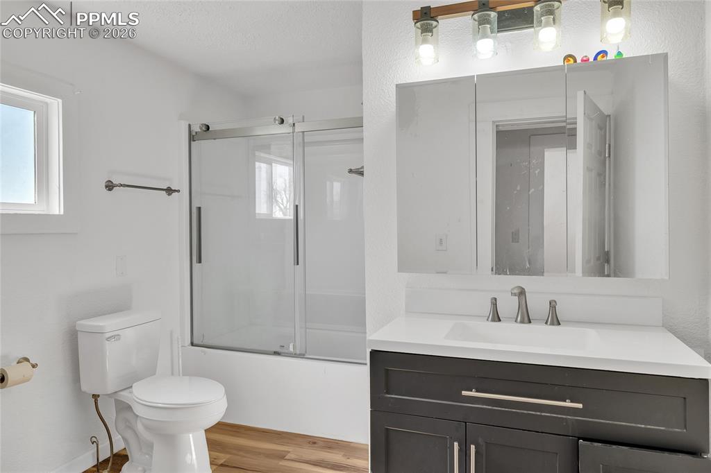 68300 Highway 50 Fowler, CO 81039 - Photo 34 of 47 ADU Bathroom with vanity, shower / bath combination with glass door, light wood-type flooring, and a textured ceiling