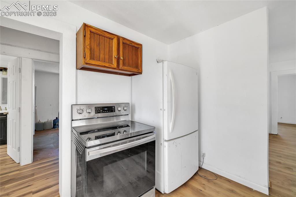 68300 Highway 50 Fowler, CO 81039 - Photo 36 of 49 ADU Kitchen with stainless steel range with electric stovetop, wood finish cabinetry, light wood-style flooring, and freestanding refrigerator