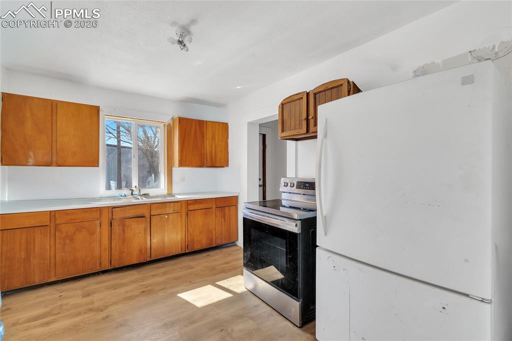 68300 Highway 50 Fowler, CO 81039 - Photo 37 of 49 ADU Kitchen featuring freestanding refrigerator, stainless steel electric range oven, wood finish cabinetry, light countertops, and light wood-type flooring