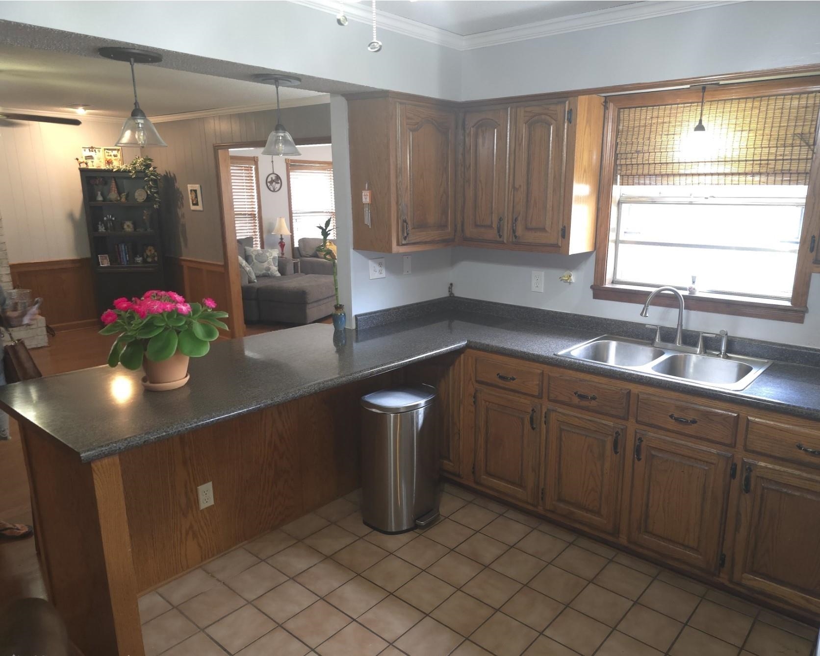 8724 Fay Road Memphis, TN 38018 - Photo 8 of 26 Kitchen with dark countertops, crown molding, a peninsula, decorative light fixtures, and wood finish cabinetry