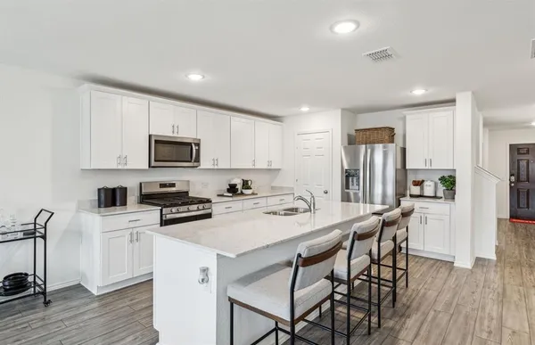 a kitchen with a table a refrigerator a cabinets and stools