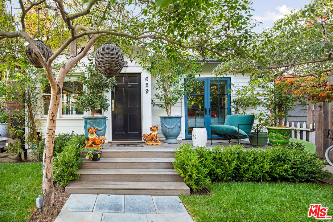 a view of a patio with couches table and chairs and potted plants and large trees