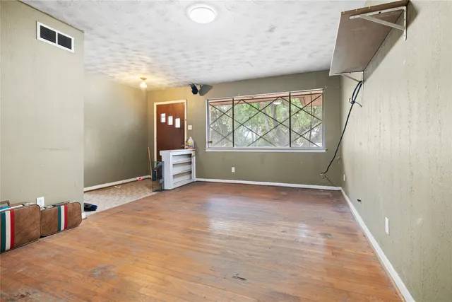 a view of an empty room with a window and wooden floor