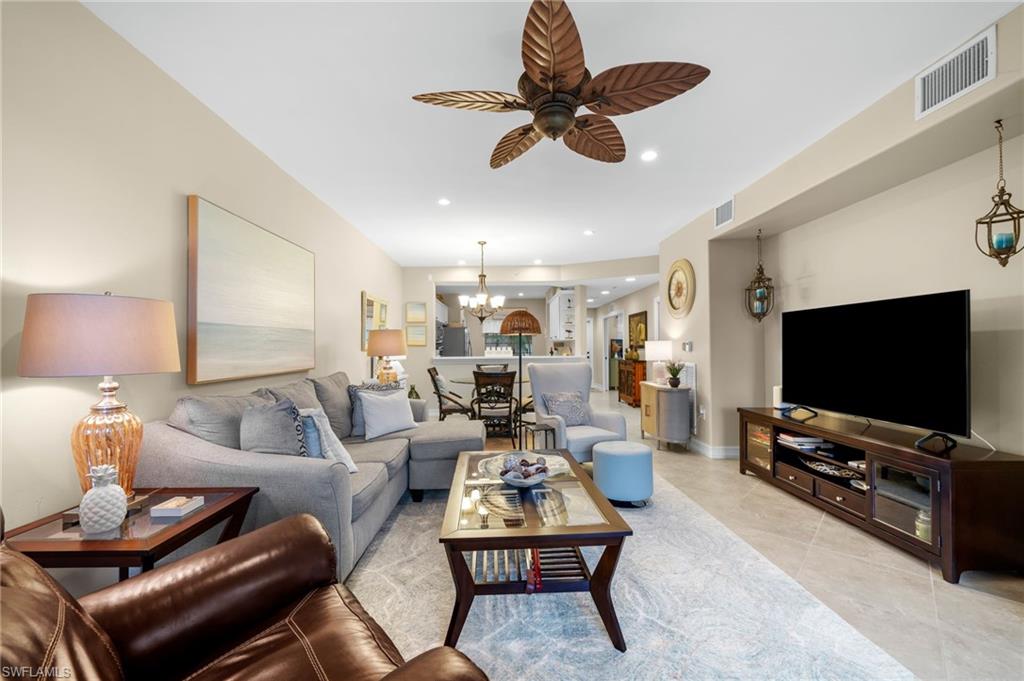 9128 Michael Circle, Unit 9 Naples, FL 34113 - Photo 19 of 50 Living room with light tile floors and ceiling fan with notable chandelier