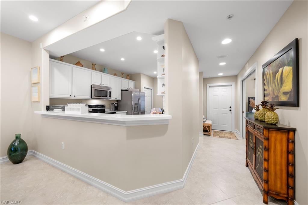 9128 Michael Circle, Unit 9 Naples, FL 34113 - Photo 21 of 50 Kitchen featuring a kitchen breakfast bar, kitchen peninsula, stainless steel appliances, light tile floors, and white cabinets