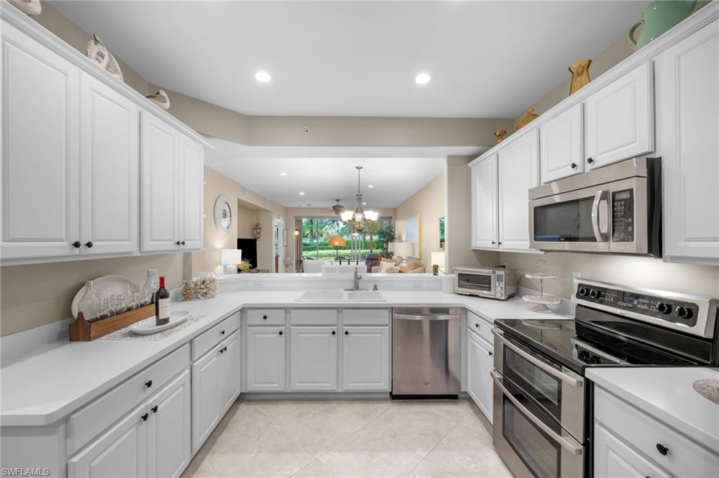 9128 Michael Circle, Unit 9 Naples, FL 34113 - Photo 7 of 50 Kitchen featuring kitchen peninsula, stainless steel appliances, light tile floors, sink, and white cabinets
