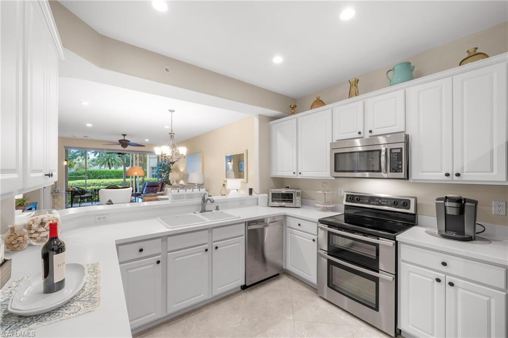9128 Michael Circle, Unit 9 Naples, FL 34113 - Photo 8 of 50 Kitchen featuring kitchen peninsula, stainless steel appliances, light tile flooring, ceiling fan with notable chandelier, and sink