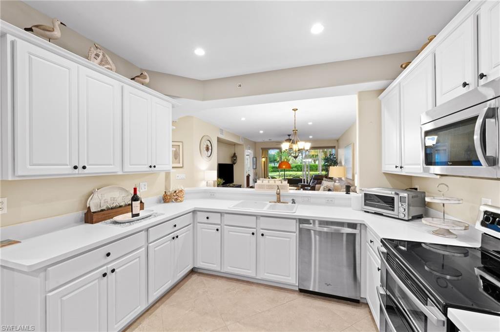 9128 Michael Circle, Unit 9 Naples, FL 34113 - Photo 9 of 50 Kitchen with kitchen peninsula, white cabinetry, appliances with stainless steel finishes, sink, and light tile floors