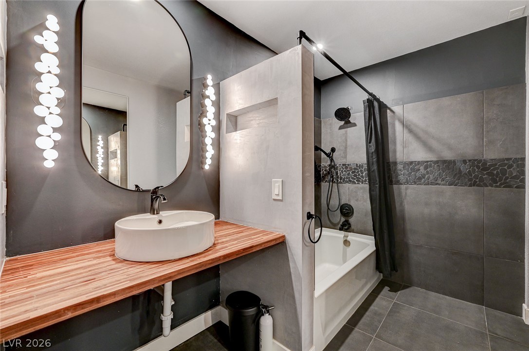 4153 Woodcrest Road Las Vegas, NV 89121 - Photo 41 of 58 A stylish bathroom featuring a vessel sink on a wooden countertop and a modern shower/tub combination.
