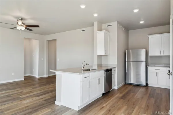 a kitchen with a refrigerator a sink and dishwasher with wooden floor