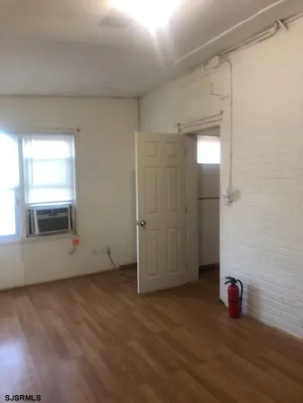 an empty room with wooden floor and window