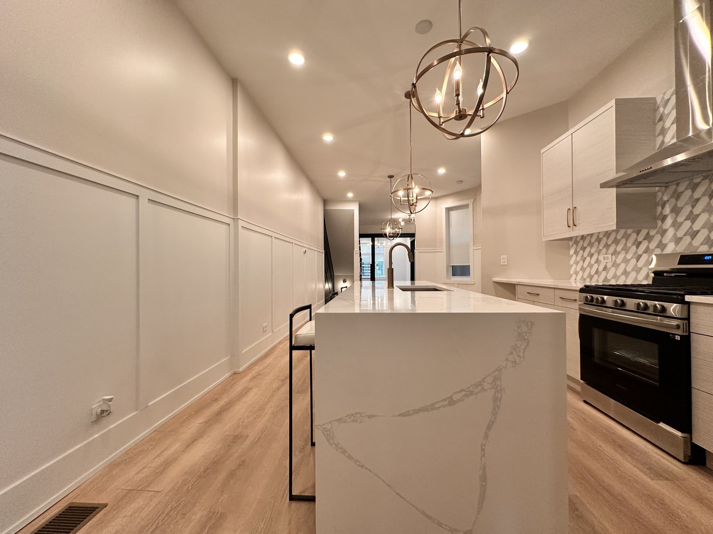 4409 South Prairie Avenue Chicago, IL 60653 - Photo 22 of 44 a large kitchen with stainless steel appliances granite countertop a stove and a chandelier