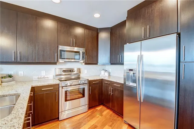 a kitchen with stainless steel appliances granite countertop a sink a stove a refrigerator and a microwave