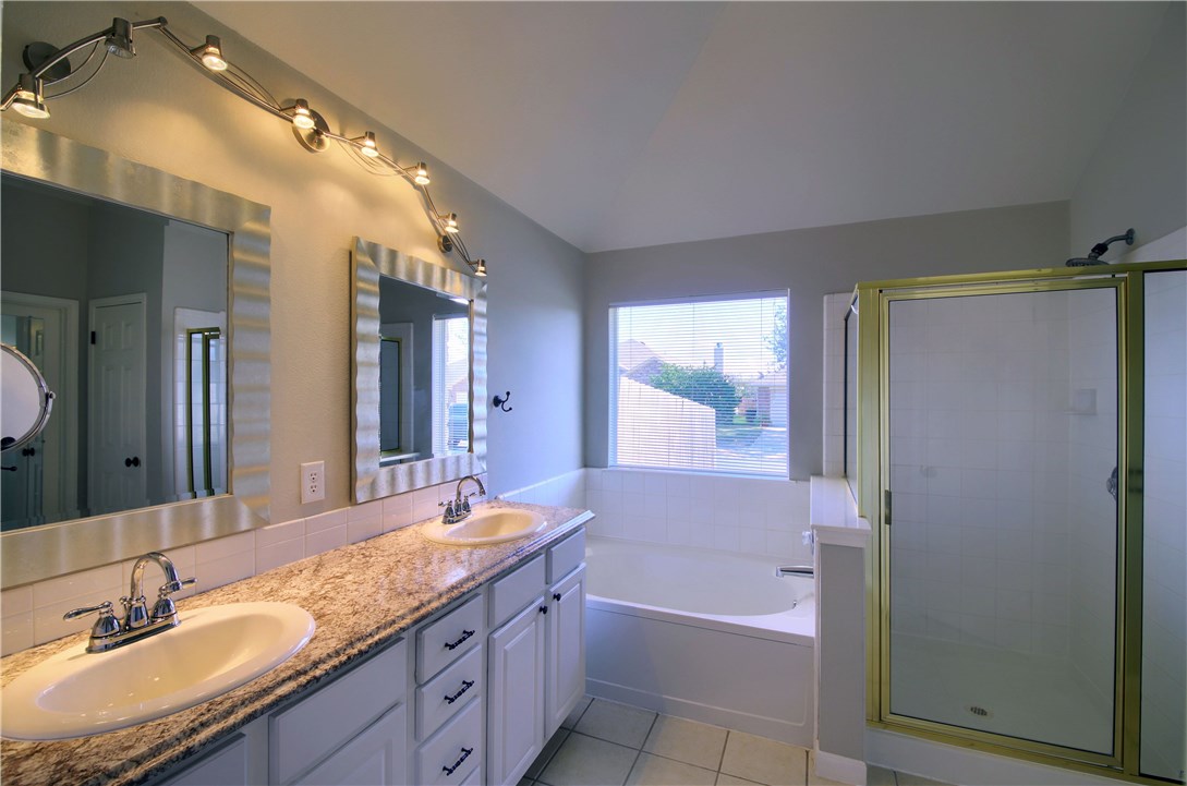 129 Copperwood Loop Round Rock, TX 78665 - Photo 24 of 30 a bathroom with a granite countertop bathtub shower sink and mirror
