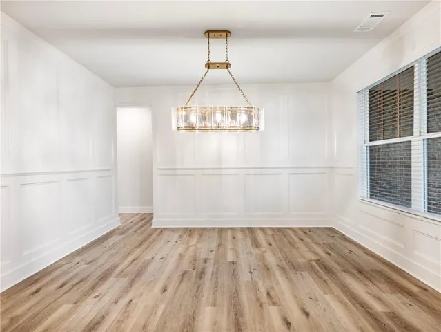 an empty room with wooden floor white walls and windows