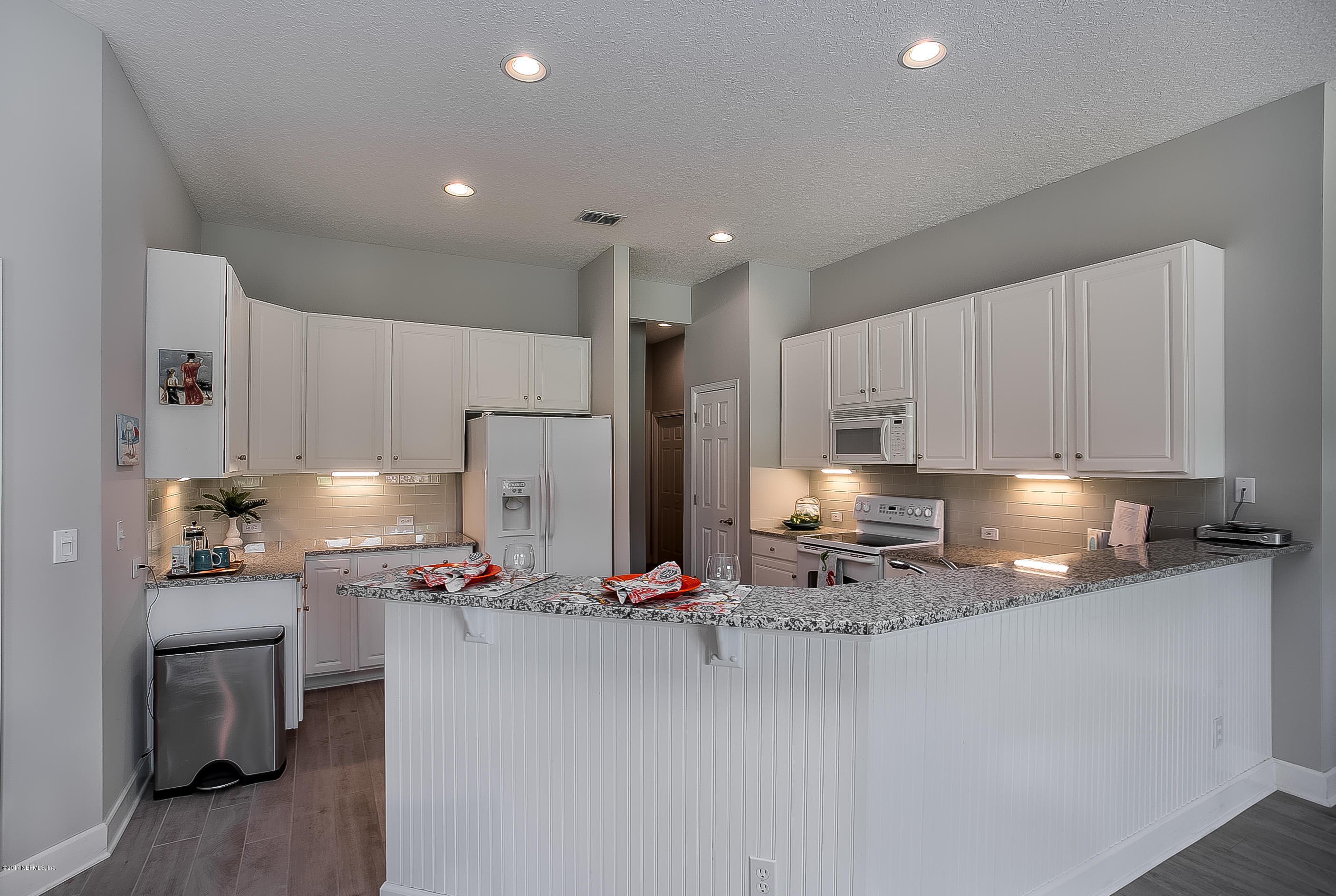261 North Mill View Way Ponte Vedra Beach, FL 32082 - Photo 7 of 27 a kitchen with kitchen island granite countertop cabinets and refrigerator