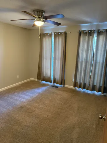 an empty room with a chandelier fan and a window