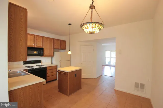 a kitchen with a refrigerator a stove cabinets and a dining table