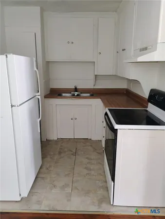 a kitchen with a refrigerator sink and cabinets