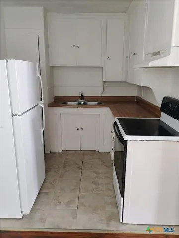 a kitchen with a refrigerator sink and cabinets