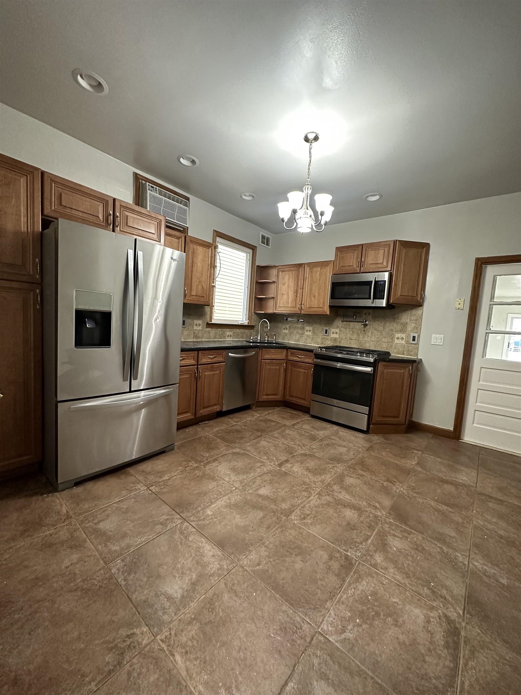 172 West 25th Street, Unit 2 Bayonne, NJ 07002 - Photo 2 of 11 a kitchen with stainless steel appliances a stove a refrigerator a sink a stove a microwave a center island and furniture