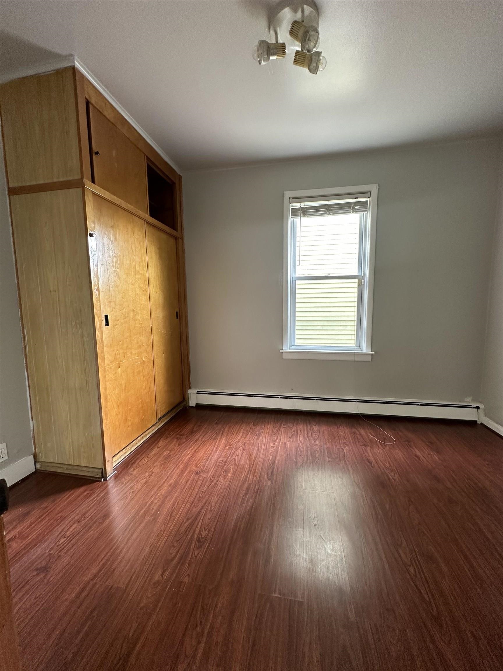 172 West 25th Street, Unit 2 Bayonne, NJ 07002 - Photo 7 of 11 an empty room with wooden floor and windows