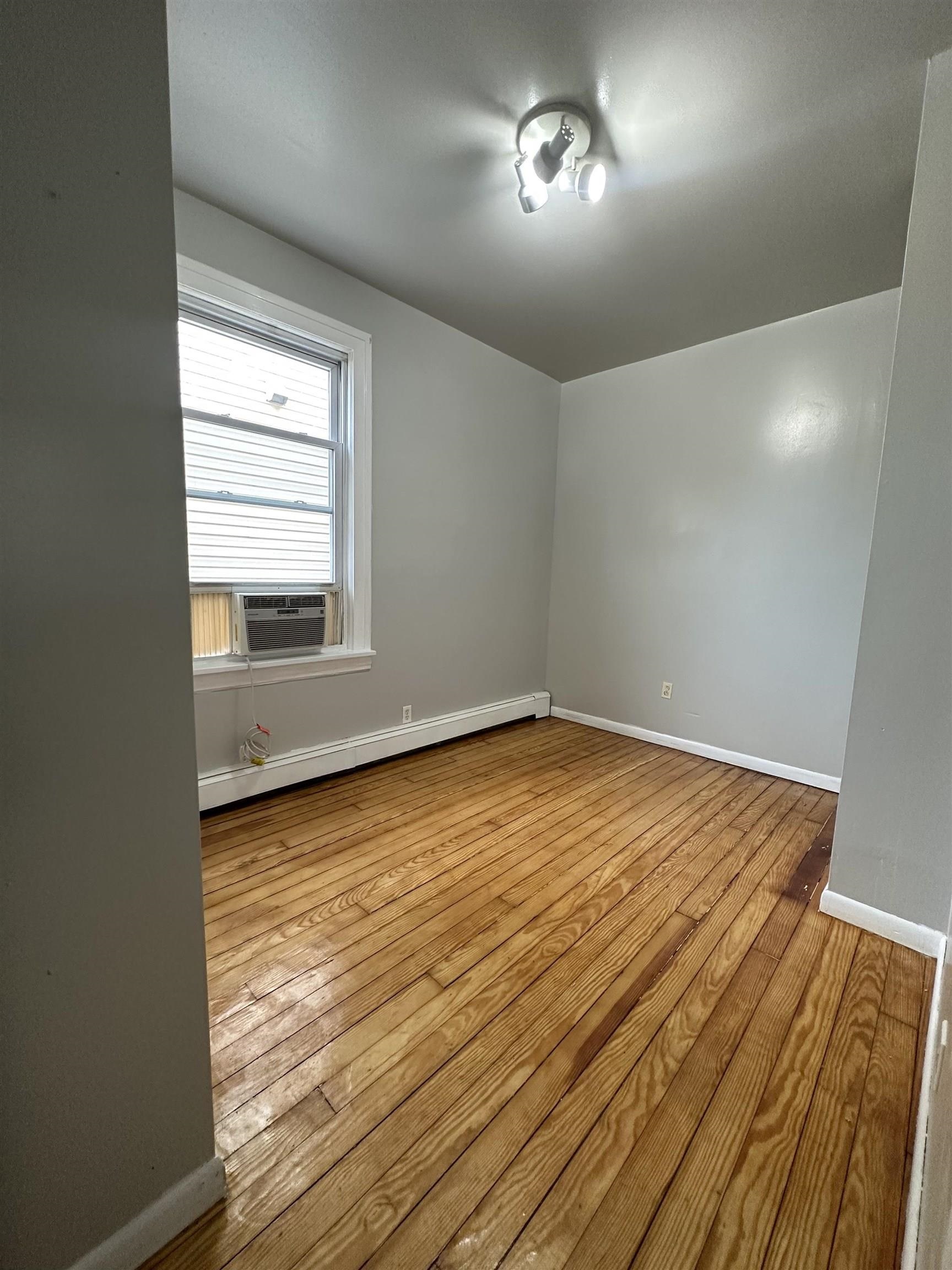 172 West 25th Street, Unit 2 Bayonne, NJ 07002 - Photo 10 of 11 wooden floor in an empty room with a window